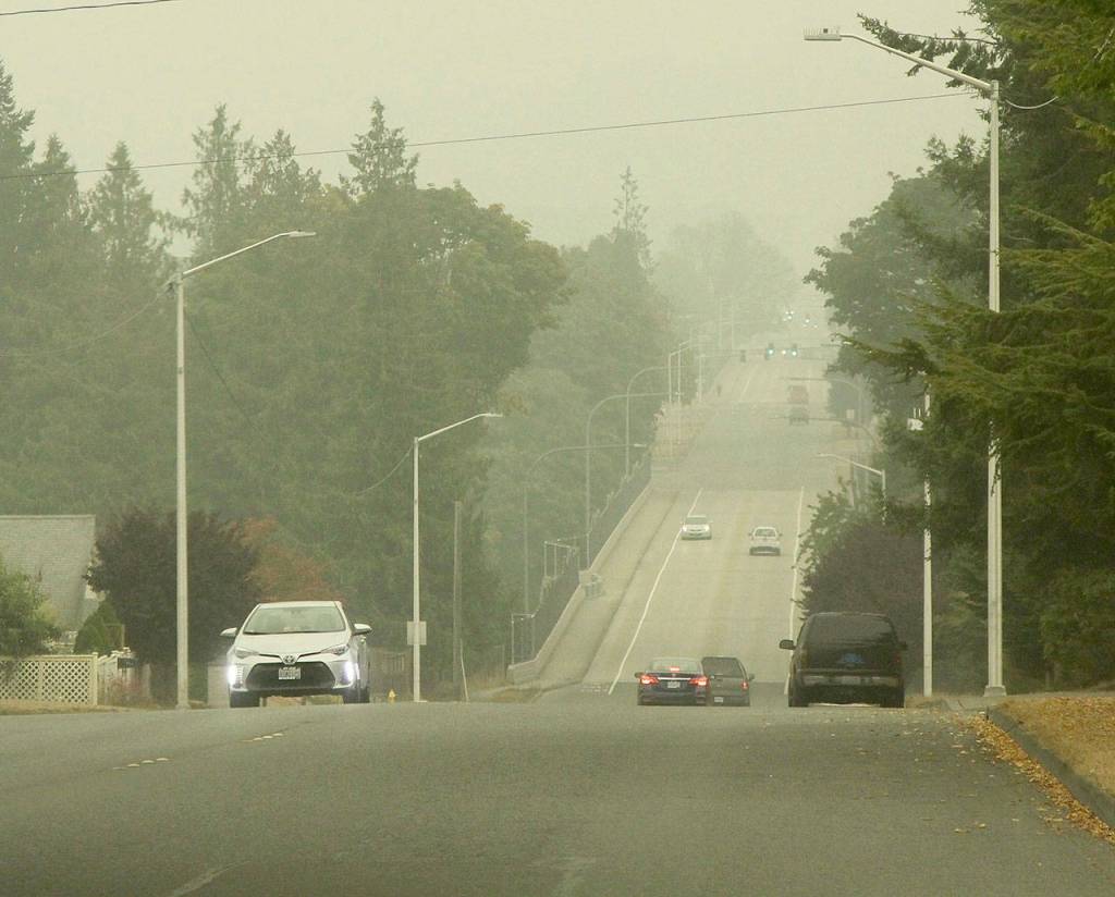 Smoke and a low marine layer had cars turning their headlights on while driving down 8th Street on Saturday morning in Port Angeles. (Dave Logan/For Peninsula Daily News)