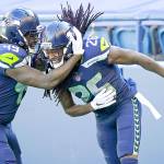 Seattle Seahawks cornerback Shaquill Griffin (26) is greeted by his twin brother, outside linebacker Shaquem Griffin (49), after Shaquill Griffin intercepted a pass against the Dallas Cowboys during the first half Sunday in Seattle. (Elaine Thompson/The Associated Press)