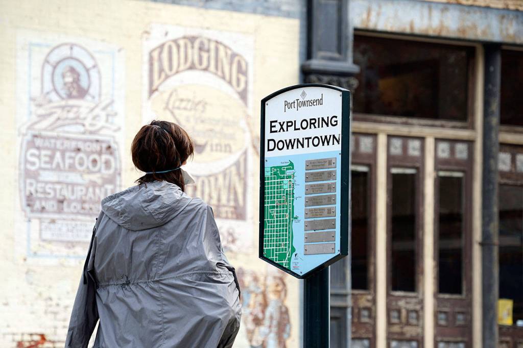 Julie Betts of Santa Rosa, Calif., studies one of 10 outdated downtown merchant information signs Thursday, Oct. 1, 2020, at the corner of Water and Taylor streets in Port Townsend. (Nicholas Johnson/Peninsula Daily News)