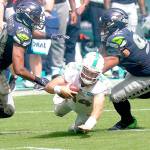 Miami Dolphins quarterback Ryan Fitzpatrick (14) falls as Seattle Seahawks outside linebacker K.J. Wright (50) and defensive tackle Bryan Mone (92) attempt to tackle, during the second half of an NFL football game, Sunday, Oct. 4, 2020, in Miami Gardens, Fla. (AP Photo/Lynne Sladky)