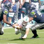 Miami Dolphins quarterback Ryan Fitzpatrick (14) falls as Seattle Seahawks outside linebacker K.J. Wright (50) and defensive tackle Bryan Mone (92) attempt to tackle, during the second half of an NFL football game Sunday, Oct. 4, 2020, in Miami Gardens, Fla. (Lynne Sladky/Associated Press)