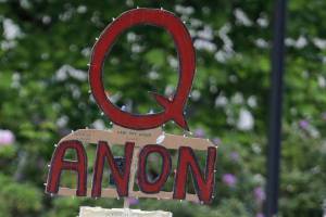 FILE - In this May 14, 2020, file photo, a person carries a sign supporting QAnon at a protest rally in Olympia, Wash. Facebook said Tuesday, Oct. 6, 2020, that it will remove Facebook pages, groups and Instagram accounts for “representing QAnon.” (AP Photo/Ted S. Warren, File)