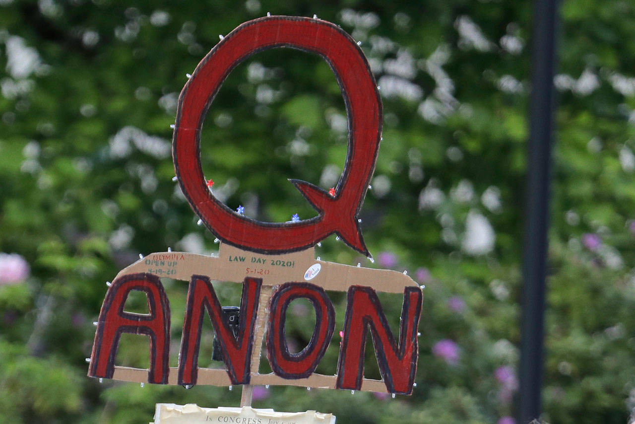 In this May 14, 2020, file photo, a person carries a sign supporting QAnon at a protest rally in Olympia, Wash. Facebook said Tuesday, Oct. 6, 2020, that it will remove Facebook pages, groups and Instagram accounts for representing QAnon. (AP Photo/Ted S. Warren/Associated Press file)