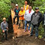 When a footbridge over Lonesome Creek, located on the popular West End’s LaPush Beach Trail, needing replacing, three organizations collaborated on it. Quileute Tribal Council provided materials, including 30-foot-long steel I-beams for the bridge stringers, the Olympic National Park provided the drawings and oversight of the project and Back Country Horsemen Mt Olympus Chapter members provided volunteers to remove the old bridge and replace it with materials that will last many years. From left, Mt. Olympus volunteers Mike McCracken, Larry Baysinger, Rich James and Ray Sutherland (orange hat). Representing the Quileute Tribal Council are, from left, and Tom Jackson, Doug Woodruff,  Skylar Foster and Tony Foster. (Sherry Baysinger)