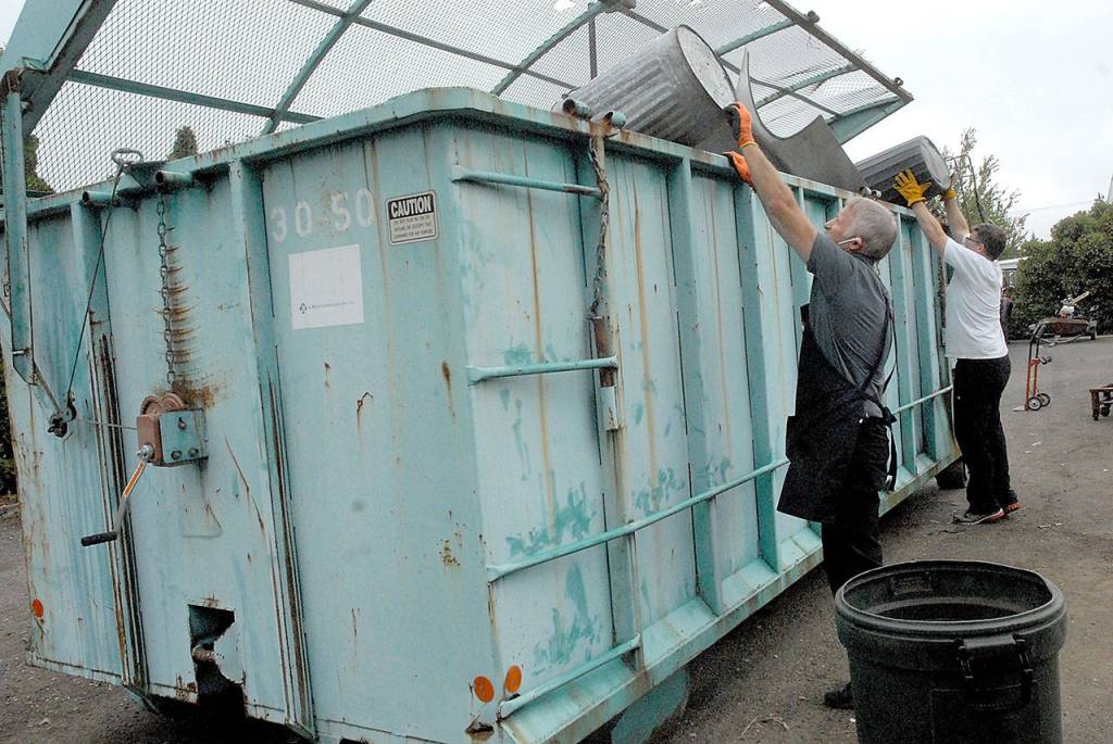 Safeway clerk Fritz Clemens II, front, and store director Michael LaGrange empty trash cans of trash into a refuse bin behind the Lincoln Street store Friday in Port Angeles. (Keith Thorpe/Peninsula Daily News)
