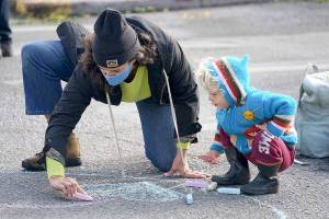 Holly Jarnagin, left, and 2-year-old Frankie Rezendes of Port Townsend make chalk art in the intersection of Lawrence and Tyler streets Saturday during the farmers market in uptown Port Townsend. City staff set up a booth and distributed chalk during Saturday's market, encouraging people to draw their hopes and dreams for the city's future. (Nicholas Johnson/Peninsula Daily News)