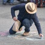 Danny Milholland of Port Townsend makes chalk art in the intersection of Lawrence and Tyler streets Saturday during the farmers market in uptown Port Townsend. (Nicholas Johnson/Peninsula Daily News)