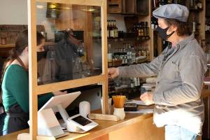 Port Townsend resident Mike Marston checks out of Aldrich's Market Tuesday with barista and cashier Sarah Marx. The 125-year-old store reopened Saturday after closing in early spring and being bought by new owners and renovated over the summer. (Zach Jablonski/Peninsula Daily News)