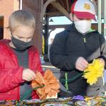 Alec Naddy, 6, left, and his brother, Porter Nady, 9, both of Bothell, create tissue paper marigolds on Saturday at the Port Angeles Farmers Market. The flowers will become part of a Día de los Muertos ofrenda, a display of mementos honoring deceased loved ones for the Day of the Dead, which will be set up at The Wharf mall next week. The craft event is co-sponsored by the Juan de Fuca Foundation for the Arts and North Olympic Library System. (Keith Thorpe/Peninsula Daily News)