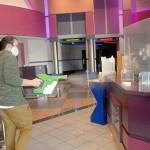 Deer Park Cinema manager Casey Chapman sprays disinfectant mist around the concession stand of the Port Angeles theater complex lobby on Thursday in preparation for reopening on Oct. 30. (Keith Thorpe/Peninsula Daily News)