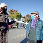 Amanda Milholland, left, and Deirdre Morrison talk while strolling through the Port Townsend Farmers Market on Saturday in uptown Port Townsend. Morrison is taking over for Milholland as market manager for the Jefferson County Farmers Markets. While Milholland has started her new role as produce manager at the Port Townsend Food Co-op, she plans to train her successor through the end of the market season in December. (Nicholas Johnson/Peninsula Daily News)