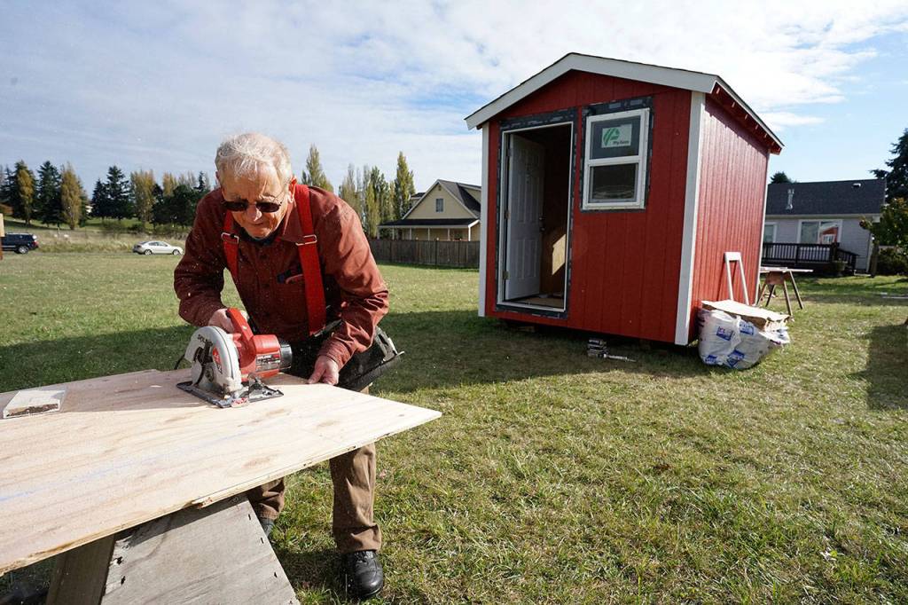 Port Townsend resident Peter Bonyun uses a saw to cut a piece of plywood to size while building an emergency shelter Thursday afternoon in Port Townsend. Bonyun is one of the people who started the Community Build Project, which aims to provide temporary-use shelters for the homeless during the coming winter months. (Nicholas Johnson/Peninsula Daily News)