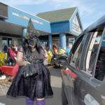 Keith Thorpe/Peninsula Daily NewsB
Kayleen McDonald of the Sequim unit of the Boys & Girls Clubs of the Olympic Peninsuila delivers bagged lunches to a waiting car as unit director Tessa Jackson looks on at left during a drive-thru Halloween in front of the organization's Sequim facility. Besides lunch bags, trick-or-treaters were offered hats, treats and coloring books.