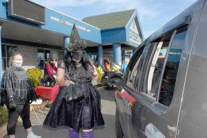 Keith Thorpe/Peninsula Daily NewsB
Kayleen McDonald of the Sequim unit of the Boys & Girls Clubs of the Olympic Peninsuila delivers bagged lunches to a waiting car as unit director Tessa Jackson looks on at left during a drive-thru Halloween in front of the organization's Sequim facility. Besides lunch bags, trick-or-treaters were offered hats, treats and coloring books.
