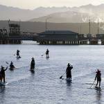 Cackling all the way, seven witches celebrate Halloween by paddling through Port Townsend Bay under a setting sun Saturday evening, with the ferry terminal, the paper mill and the Olympic Mountains in the background. This coven includes Juanita Maples, Shannon Murock, Heather Sessions, Karyn Stillwell, Adrian Olson, Amy Pacifera and Lily Murock. (Nicholas Johnson/Peninsula Daily News)