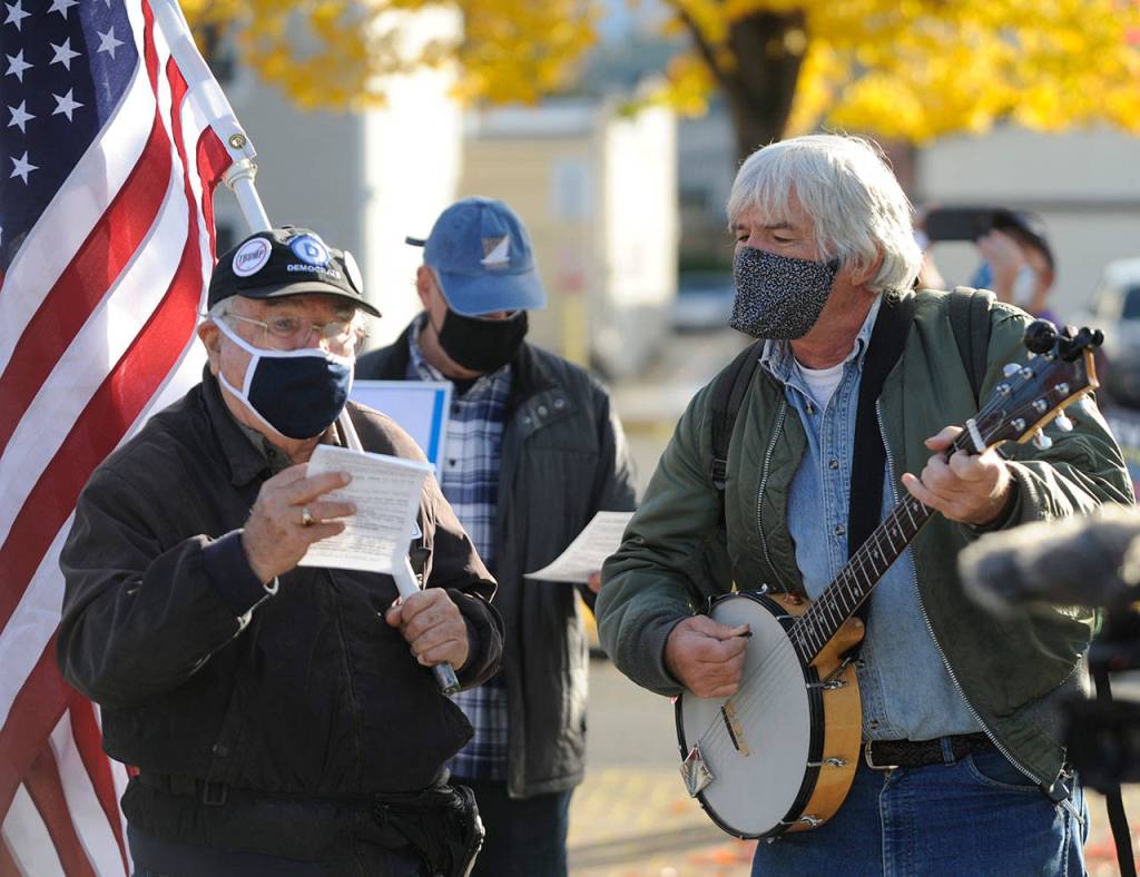 Tim Wheeler, left, and a group of about 40 individuals sing Woody Guthries This Land Is Your Land, accompanied by Steve Koehler on banjo, at the Sequim Civic Center on Wednesday afternoon. (Michael Dashiell/Olympic Peninsula News Group)