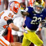 Notre Dame running back Kyren Williams (23) fends off Clemson Tigers safety Nolan Turner (24) on his way to a touchdown during the first quarter of an NCAA college football game Saturday, Nov. 7, 2020, in South Bend, Ind. (Matt Cashore/Pool Photo via AP)