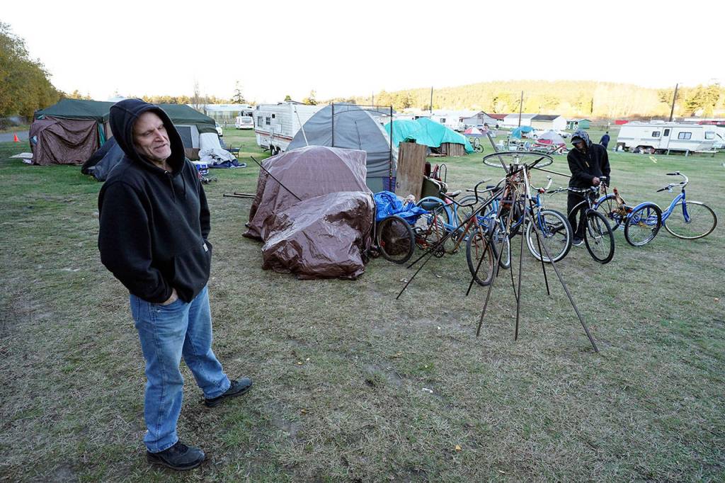 Brian Thompson, left, reflects on his time living at the Jefferson County Fairgrounds campground Sunday as Daniel Overbey organizes his recently relocated campsite on a cold, windy November day in Port Townsend. (Nicholas Johnson/Peninsula Daily News)