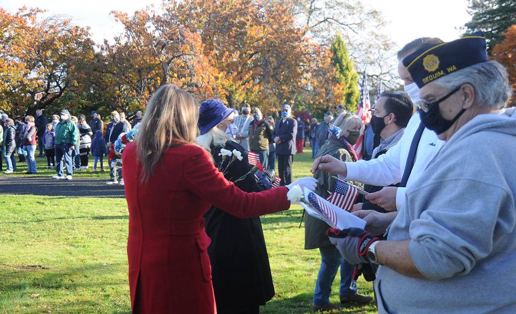Members of the Daughters of the American Revolution-Michael Trebert Chapter hand out red, white and blue flowers to veterans and their families at Pioneer Memorial Park on Wednesday. (Michael Dashiell/Olympic Peninsula News Group)