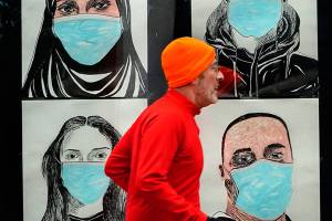 FILE - In this Nov. 16, 2020, file photo, a runner passes by a window displaying portraits of people wearing face coverings to help prevent the spread of the coronavirus in Lewiston, Maine. A deadly rise in COVID-19 infections is forcing state and local officials to adjust their blueprints for fighting a virus that is threatening to overwhelm health care systems. Schools are scrapping plans to reopen classrooms. More states are adopting mask mandates. (AP Photo/Robert F. Bukaty, File)