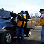 George Dooley, left, and Edward Alders with the Sequim Valley Lions Club work together to load a vehicle with food during the Family Holiday Meal Bag distribution program in Sequim. (Matthew Nash/Olympic Peninsula News Group)