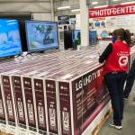 A sales associate helps customers as they consider the purchase of a big-screen television at a Costco warehouse on Wednesday, Nov. 18, 2020, in Sheridan, Colo.  U.S. consumer confidence fell to a reading of 96.1 in November as rising coronavirus cases pushed Americans’ confidence down to the lowest level since August. The Conference Board said the November reading represented a drop from a revised 101.4 in October.  (AP Photo/David Zalubowski)