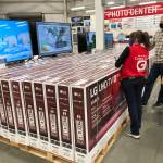 A sales associate helps customers as they consider the purchase of a big-screen television at a Costco warehouse Wednesday, Nov. 18, 2020, in Sheridan, Colo. U.S. consumer confidence fell to a reading of 96.1 in November as rising coronavirus cases pushed Americans confidence down to the lowest level since August. The Conference Board said the November reading represented a drop from a revised 101.4 in October. (David Zalubowski/The Associated Press)