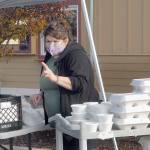 Sendy Alvarez, manager of Hardys Market, takes a dinner order outside the Sequim convenience store and deli on Thanksgiving Day. In an annual tradition, the market gave away traditional turkey dinners to people, foregoing inside service this year in favor of walk-up delivery to adhere to COVID-19 distancing guidelines. (Keith Thorpe/Peninsula Daily News)