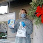 Quintana Kelley, library assistant at the Jefferson County Library, holds the gingerbread house-making kit that the library is passing out for its annual edible house-building competition. Registration to pick up the free kits closes Saturday, and photos of the finished houses are due by Dec. 13. (Zach Jablonski/Peninsula Daily News)