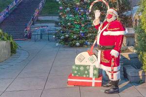 Santa Claus waves to a few spectators after pulling the lever to light the community Christmas tree Saturday at Haller Fountain in Port Townsend. (Steve Mullensky/For Peninsula Daily News)