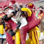 Southern California cornerback Chris Steele, left, and cornerback Olaijah Griffin, right, bring down Washington State wide receiver Renard Bell, center, after a catch during the second half of an NCAA college football game in Los Angeles on Sunday, Dec. 6, 2020. (Alex Gallardo/Associated Press)
