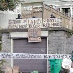 Masked protesters by an occupied home speak with a neighborhood resident opposed to their encampment and demonstration in Portland, Ore., on Wednesday, Dec. 9, 2020. Makeshift barricades erected by protesters are still up in Oregon's largest city a day after Portland police arrested about a dozen people in a clash over gentrification and the eviction of a family from a home. (AP Photo/Gillian Flaccus)