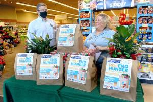 Keith Thorpe/Peninsula Daily News
Mike La Grange, manager of the Lincoln Street Safeway store in Port Angeles, left, and employee Sheryl Switer, who help organize the store's food drive, chat on Saturday next to a display of food bags for purchase to benefit the local food bank.