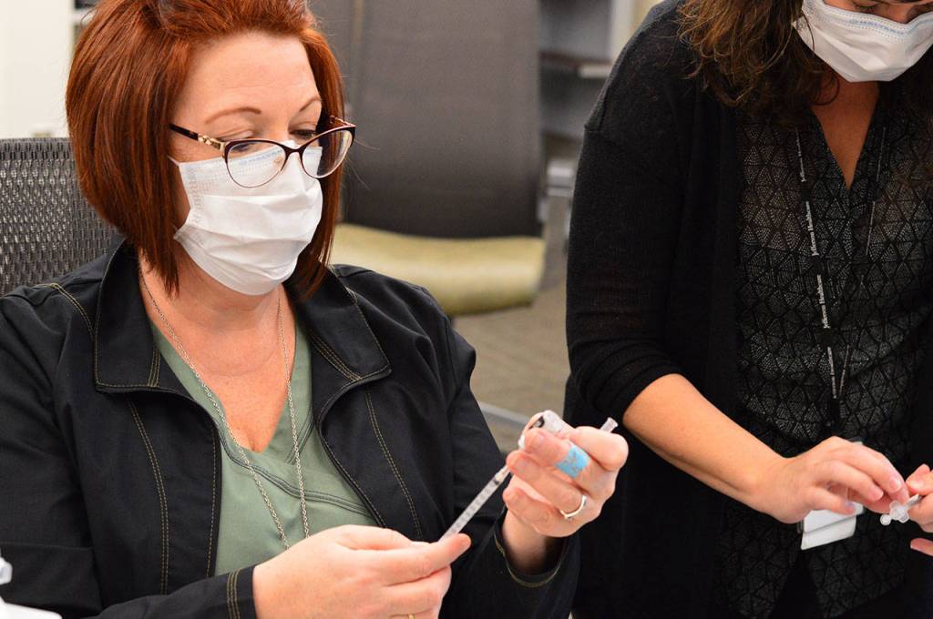 Nurse coordinator Erin Wallner, left, and clinical manager Jaimie Hoobler prepare the first COVID vaccines at Jefferson Healthcare hospital Wednesday, Dec. 16, 2020. (Diane Urbani de la Paz/Peninsula Daily News)