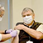 Tom Heuberger, a nurse and night supervisor at Jefferson Healthcare hospital, receives the Peninsulas second vaccination against COVID-19 on Wednesday, Dec. 16, 2020, from nurse Jess Cigalotti. (Diane Urbani de la Paz/Peninsula Daily News)