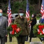 Staff Sgt. Jessica Elizalde-Broders, a U.S. Army veteran, looks to lay a ceremonial wreath at Sequim View Cemetery Saturday. In the foreground are, from left, Cmdr. Bill Benedict (U.S. Navy, ret.), Lance Cpl. Holly Rowan (U.S. Marine Corps veteran) and Cmdr. Joan Snaith (U.S. Coast Guard, Air Station Port Angeles). (Michael Dashiell/Olympic Peninsula News Group)