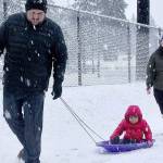 Jarrett and LeAnn Hansen took their daughter H.J., 2, out sliding just outside the fence of Elks Playfield on Pine Street on Monday during the first snow of the winter. (Dave Logan/For Peninsula Daily News)