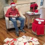 Rodney Hofman opens one of hundreds of Christmas cards sent to hime and fellow Dungeness Courte Memory Care residents following a request from Hofman's family members on social media. (Dungeness Courte Memory Care)
