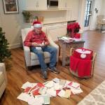 Rodney Hofman opens one of hundreds of Christmas cards sent to him and fellow Dungeness Courte Memory Care residents following a request from Hofmans family members on social media. (Photo courtesy of Dungeness Courte Memory Care)