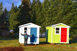 Volunteer builder Randy Welle prepares to welcome people to the Bayside Housing village in Port Hadlock. The sky-blue shelter is named Beth's House in honor of cofounder Peter Bonyun's late wife Beth Lorber.  Diane Urbani de la Paz/Peninsula Daily News