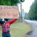 Tri-Area Community Meals board member Beau Young broadcast a message for passers-by on Friday afternoon. (Diane Urbani de la Paz/Peninsula Daily News)