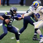 Seattle Seahawks quarterback Russell Wilson (3) tries to fend off a sack by Los Angeles Rams defensive lineman Aaron Donald (99) during the second half of an NFL football game Dec. 27 in Seattle. (Elaine Thompson/The Associated Press)