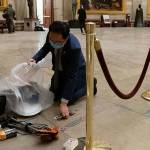 Rep. Andy Kim, D-N.J., cleans up debris and personal belongings strewn across the floor of the Rotunda in the early morning hours of Thursday after protesters stormed the Capitol in Washington on Wednesday. (AP Photo/Andrew Harnik)