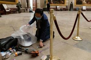 Rep. Andy Kim, D-N.J., cleans up debris and personal belongings strewn across the floor of the Rotunda in the early morning hours of Thursday after protesters stormed the Capitol in Washington on Wednesday. (AP Photo/Andrew Harnik)