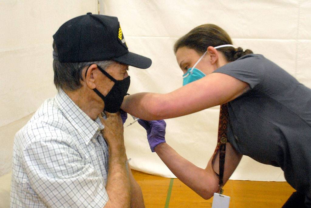 Bill Chastain of Port Angeles receives a dose of COVID-19 vaccine from Shaina Gonzales of the North Olympc Healthcare Network during Saturdays vaccination clinic at Port Angeles High School. (Keith Thorpe/Peninsula Daily News)