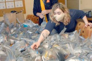 Keith Thorpe/Peninsula Daily News
Lacey Fry, development program manager for Serenity House of Clallam County, reaches for a gift bag that will be given away at the organization's Point in Time census of homeless people as Dylan Godsety, director of coordinated entry, looks on in the Serenity House office in Port Angeles. The annual count is today.