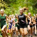 Port Angeles’ Lauren Larson, left, and Sequim’s Riley Pyeatt lead the pack at the beginning of a 2019 cross country race at Robin Hill Park. Prep runners can now run without masks at competitions after a change in state guidance. (Michael Dashiell/Olympic Peninsula News Group)