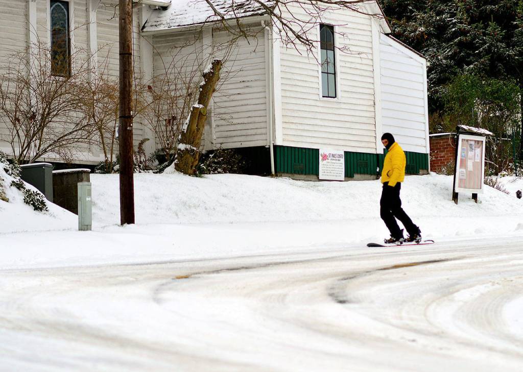 Forest Laitman takes a Saturday afternoon ride on his snowboard past St. Pauls Episcopal Church in Uptown Port Townsend. (Diane Urbani de la Paz/Peninsula Daily News)