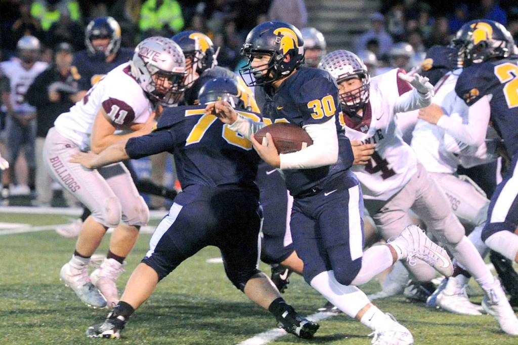 Forks Hayden Baker (30) finds running room behind the blocking of teammate Tyler Ellis (78) during a 2019 game against Montesano. (Lonnie Archibald/for Peninsula Daily News)