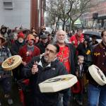 FILE - In this Jan. 6, 2020, file photo, Tony A. (Naschio) Johnson, center, elected chairman of the Chinook Indian Nation, plays a drum as he leads tribal members and supporters as they march to the federal courthouse in Tacoma, Wash., as they continue their efforts to regain federal recognition. As COVID-19 disproportionately affects Native American communities, many tribal leaders say the pandemic poses particular risks to tribes without federal recognition. The Chinook Nation received some federal funding through a local nonprofit for small tribes to distribute food to elders and help with electricity bills, tribal Johnson said. (AP Photo/Ted S. Warren, File)